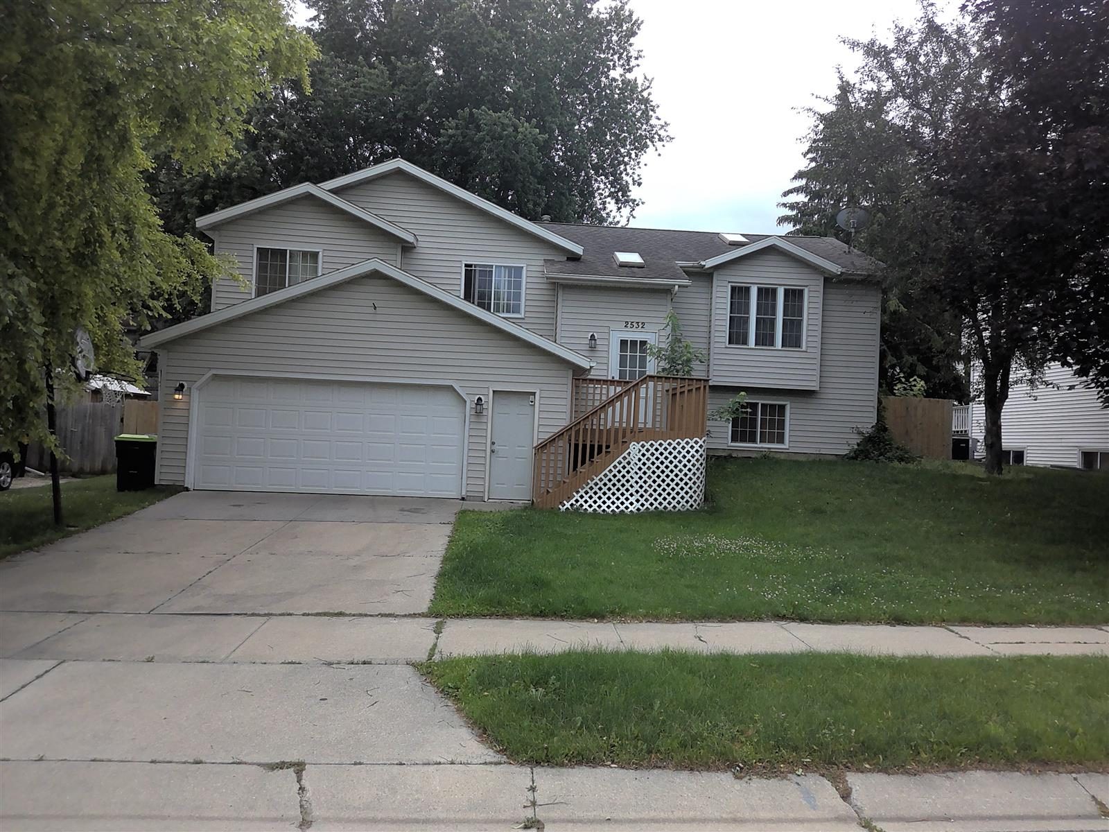BTW Residence — a two-level home with an attached garage, front deck and mature trees on a quiet residential street in northwest Rochester, Minnesota.